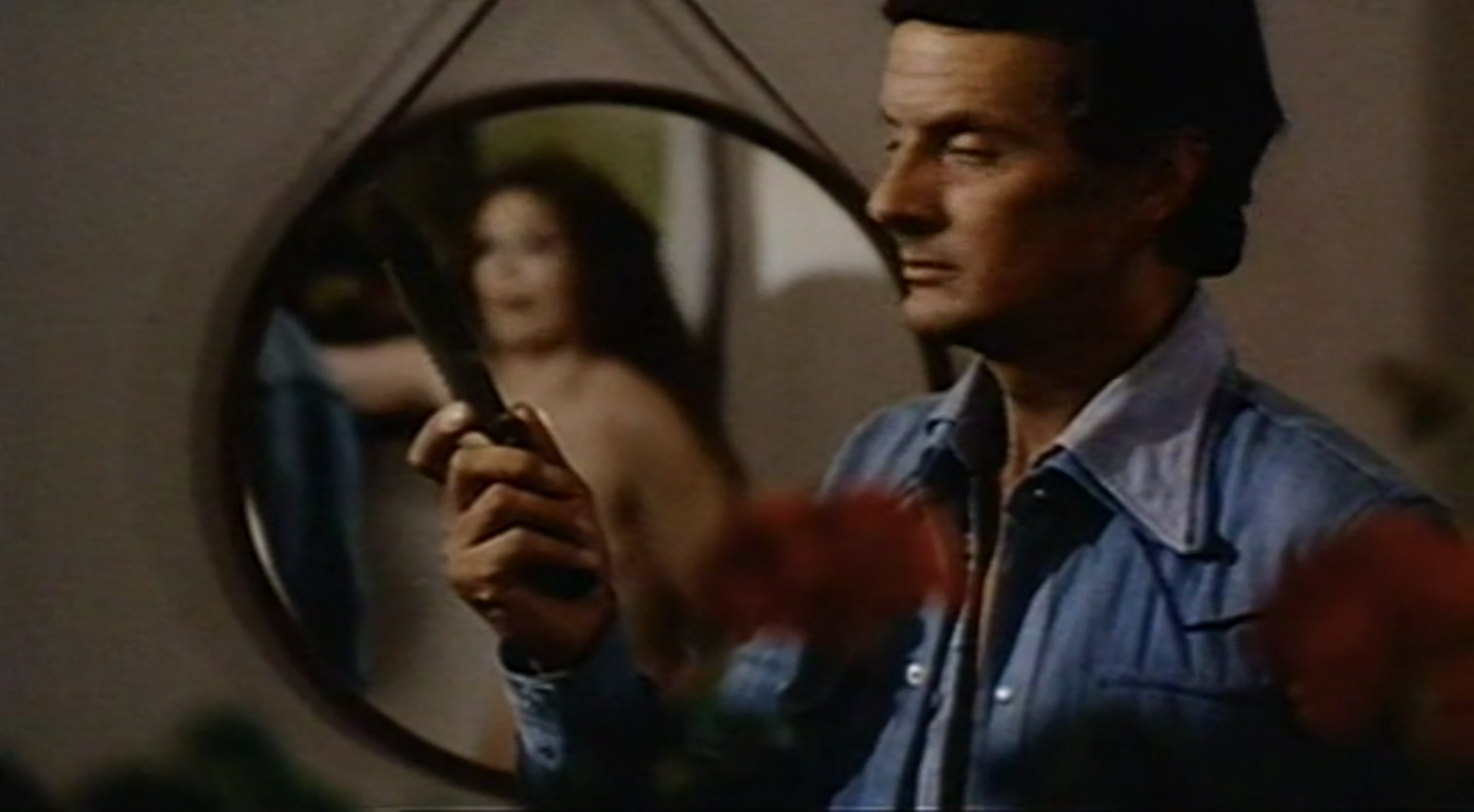 Man with knife looms as frightened woman reflected in a mirror looks on