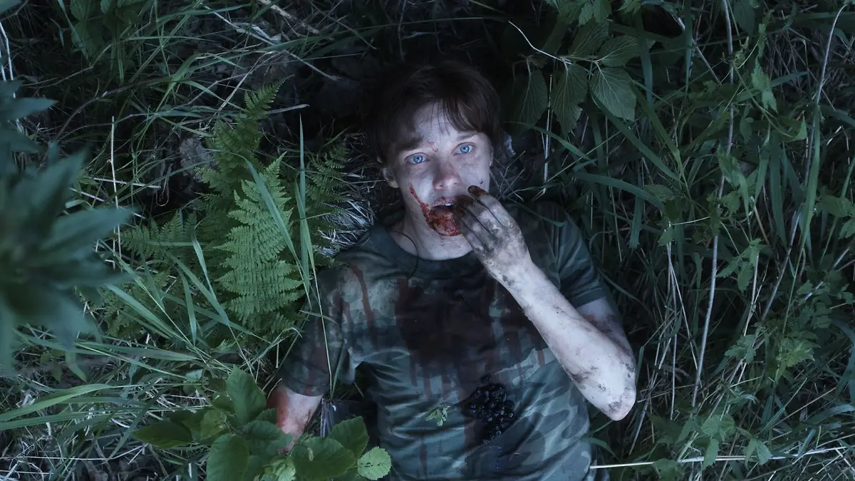 Guy with bloody face rests in grass