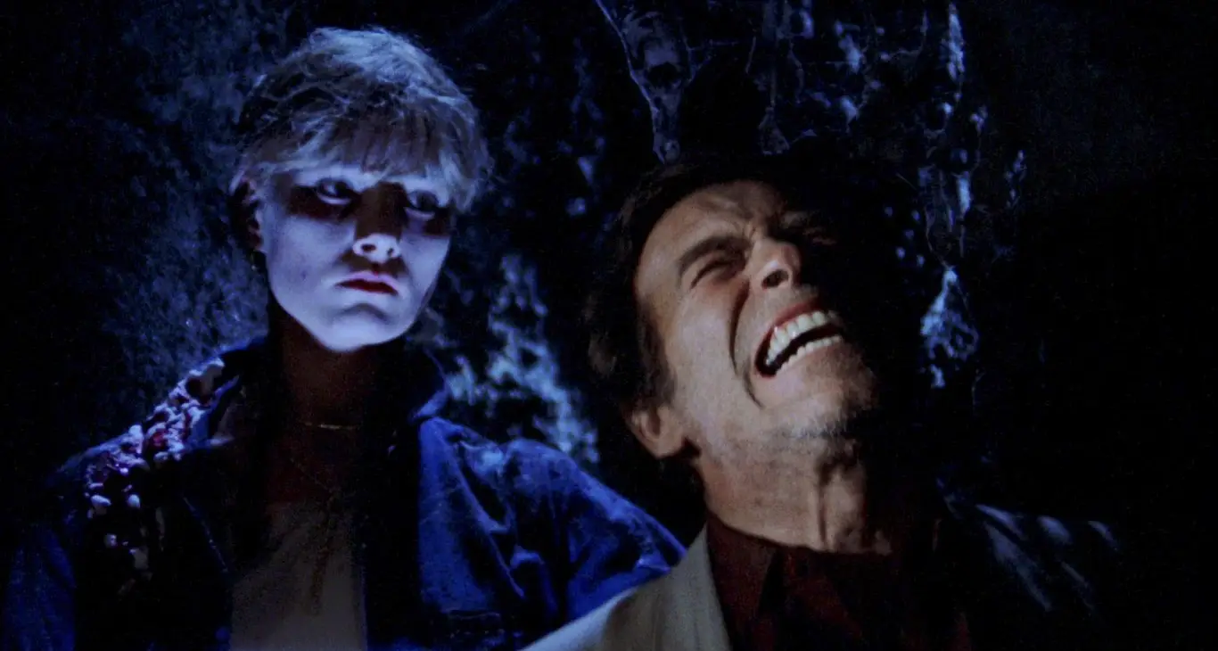 Eeerie woman looks on as man shows expression of pain