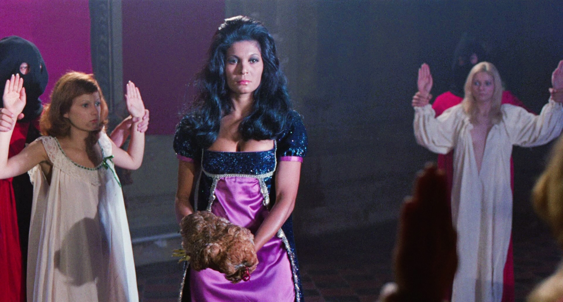 Menacing woman stands between two women prisoners
