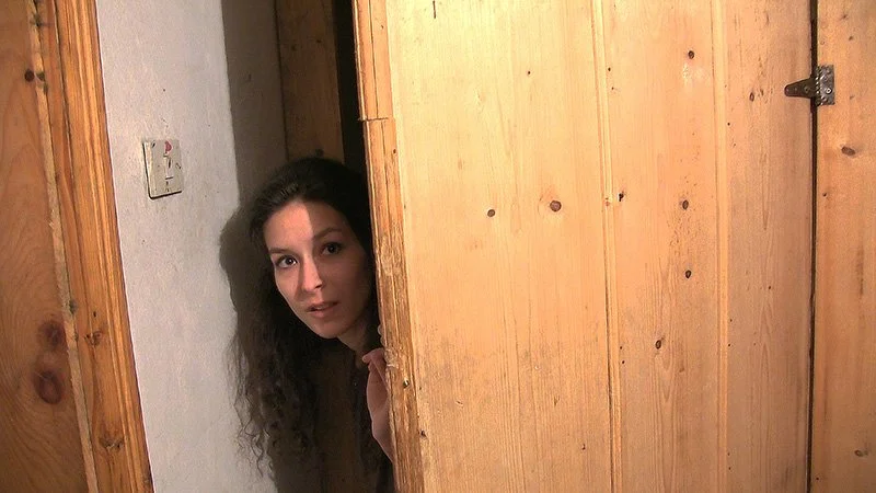 Woman looks from doorway in Be My Cat