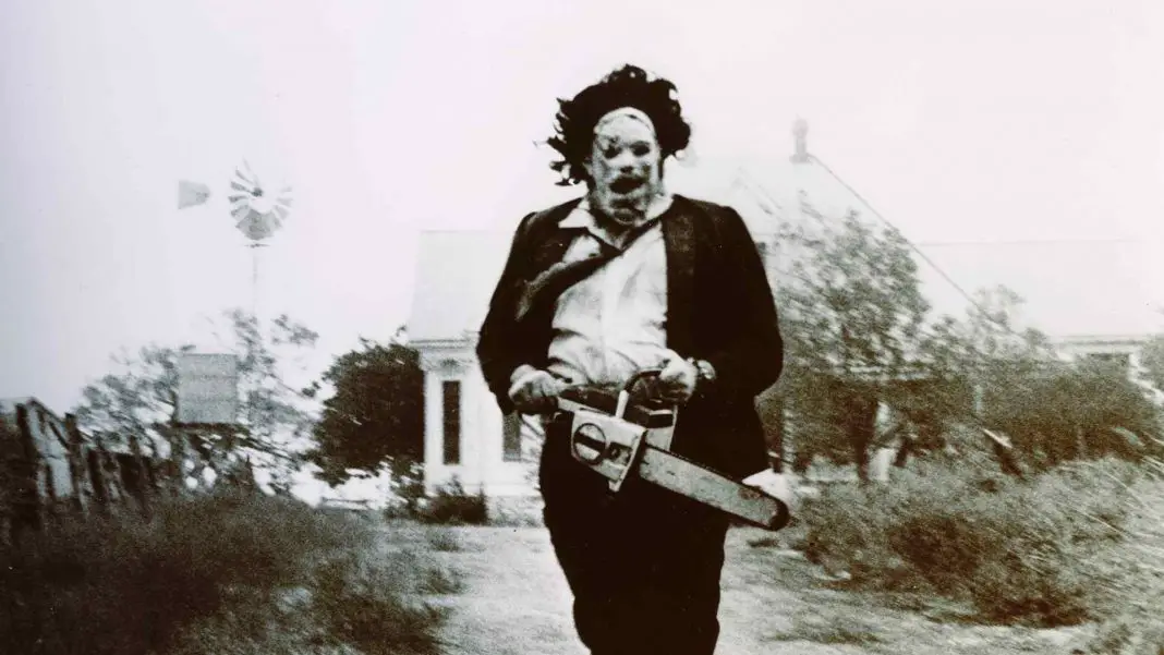 Leatherface from the movie The Texas Chainsaw Massacre chasing his victims to cut up with his chainsaw.