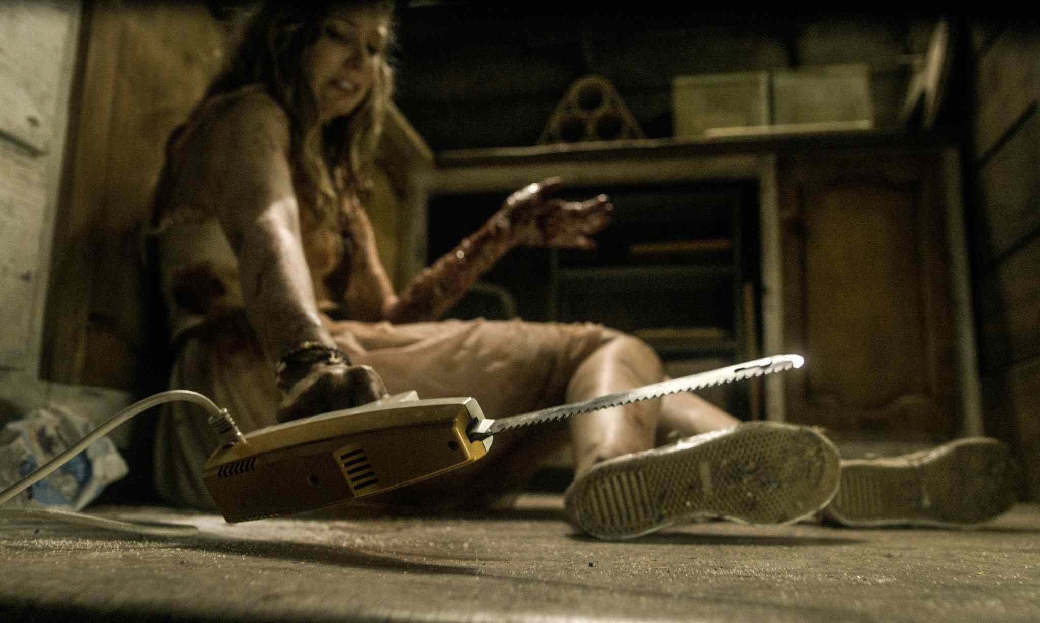 Natalie (Elizabeth Blackmore) in Fede Alvarez's Evil Dead 2013, about to cut her arm off with an electric carving knife.