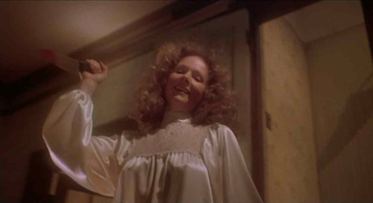 Piper Laurie as Margaret White in Carrie holds a knife over her head as she attacks her daughter.