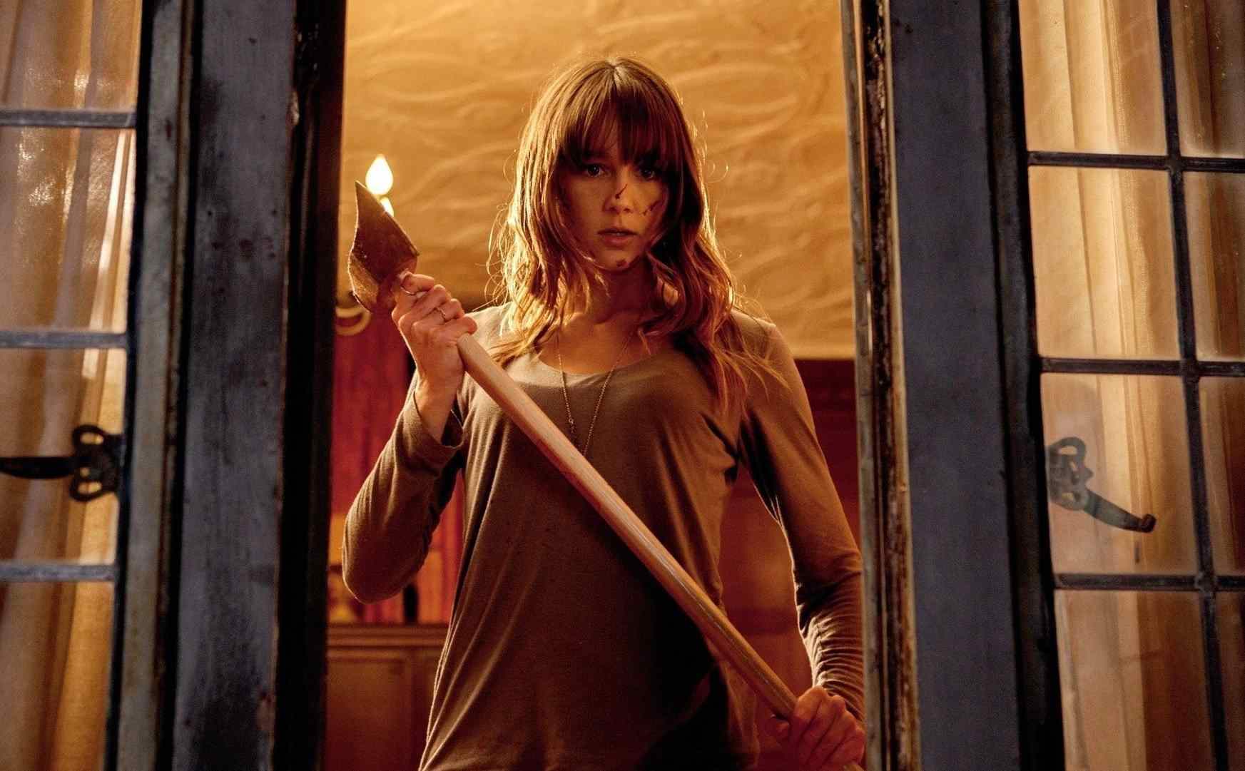 Erin holding an axe at the window in You're Next.