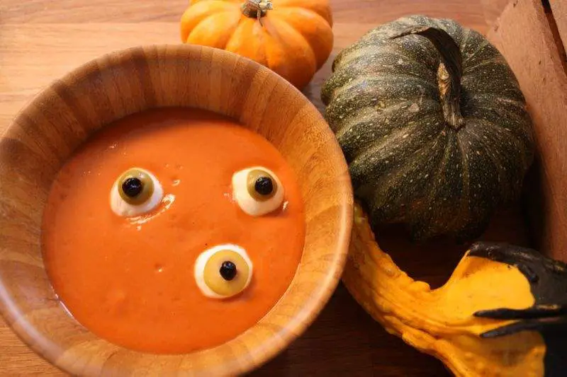 Spooky eyeball soup made out of tomato soup, mozzarella balls and olives topped with peppercorns.