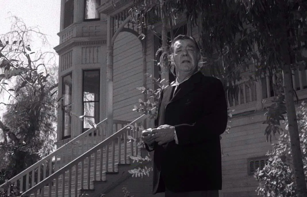Lon Chaney Jr as Bruno in Spider Baby stands in front of the Merrye house