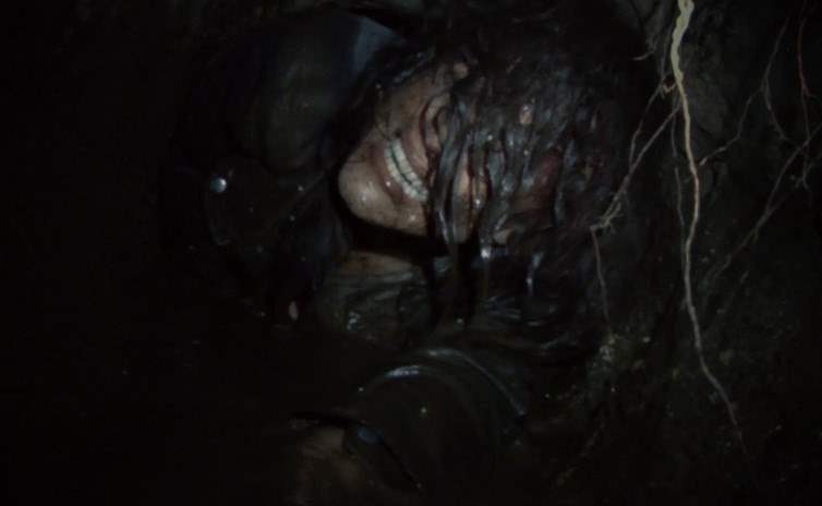Lisa crawling through a dirt tunnel in Blair Witch